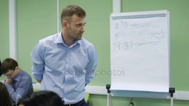 Öğretmen sınıfta öğrenciler bir sınav sırasında yakından izliyor. Üniversite sınavı. Bir dizüstü bilgisayar arka planda çalışan bir genç adam. Özenli öğretmen üniversite.