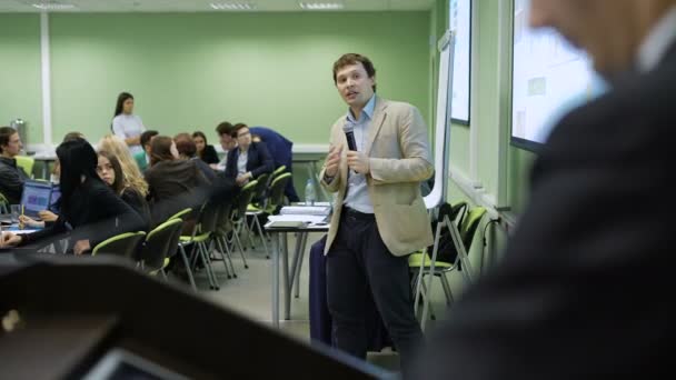 Business speaker holding a meeting for group of sales managers in the company. Business coach delivering lecture for audience with microphone pointing — Stock Video