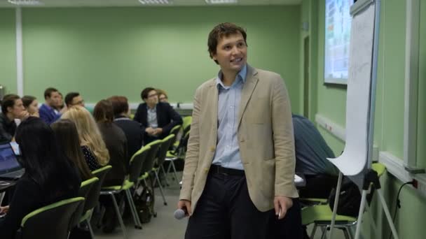 Le Président fait une pause dans son discours pour regarder l'image sur le projecteur. Jeune homme avec un microphone à la main souriant lors d'un séminaire pour étudiants .