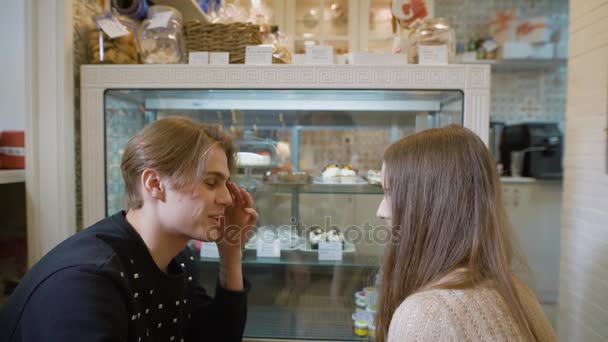 Schöne junge Leute in einem Süßwarenladen. das Mädchen und der Kerl beim ersten Date, sie haben romantische Gefühle füreinander. Vitrine angenehm dekoriert. das Mädchen mit, brünett. — Stockvideo