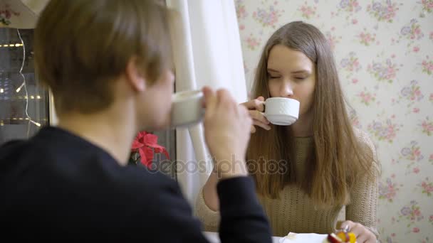 Retrato de joven morena atractiva. Hermosa chica sentada en un café con mi novio y coqueteando habla con él. Patisserie, donde café y magdalenas. Alrededor de la decoración de Navidad — Vídeos de Stock