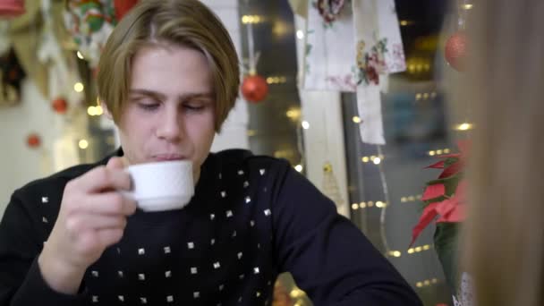 Porträtt av attraktiv ung kille, han sitter i café och leenden till sin flickvän. Mannen blondiner talar om det, det vänliga och självsäker. Troligen är det en romantisk dag i en café. — Stockvideo