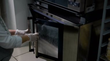 Kadın baker fırın kapakları açılır ve metal bir tepsi üzerinde yatıyor unlu, taze pişmiş ekmek, geri çeker