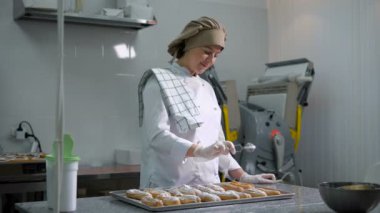 Bir tepsi eklerleri ve dikkatle hangi yatıyordu küçük hamur işi toque masaya arkasında duran neşeli kadın şeker sprinkles