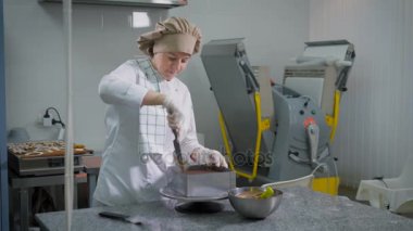 Arkasında, povarsikim pasta tablo mekanik hasat şekerleme ve çikolata kek kürek kesim metal kalıp üzerinden arka plan üzerinde ve ardından kaldırma ciddi kadın