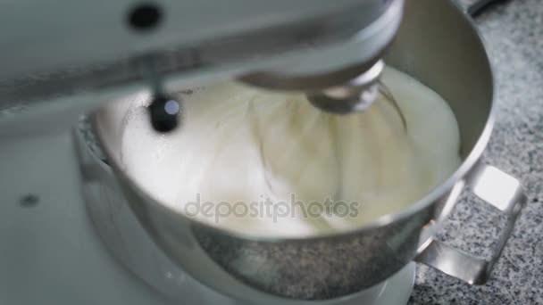 Het proces van de vorming van een weelderige crème anglaise topping in een metaalkom, die in automatische mixer staat — Stockvideo