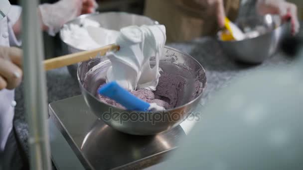 Några kockar börjar skapa ganache för framtida dessert, forma det med en silikon lameller i en metall skål, står på kanten av ett metallbord — Stockvideo