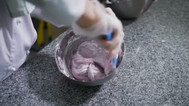 Küche in einem Süßwarenladen. Verwenden Sie das blaue Werkzeug Frau mischt Sirup rosa und weiße Masse von Eigelb. Nahe Konditor mischt auch unterschiedliche Gewichte zueinander in einer eisernen Schüssel. — Stockvideo