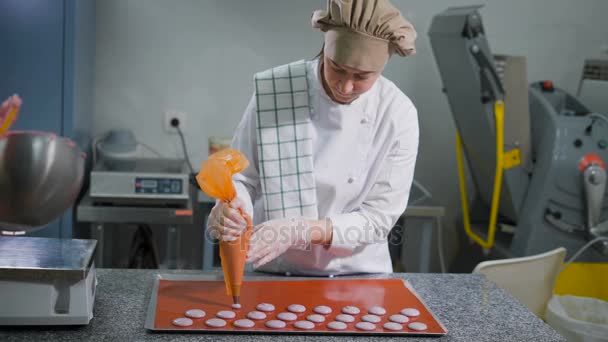 Confeiteiro com seringa de pastelaria faz cookies do mesmo tamanho antes de assar na cozinha. Sobremesa crua no convés. Ferramentas de cozinha para cozinhar doces. Assistente cozinheiro limpo tigela de creme . — Vídeo de Stock