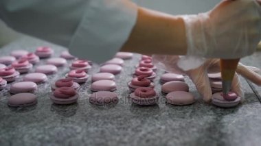 Şekerci dükkânı. Fransızca macaroons dekorasyon. Eldiven bir şekerci dükkanında çalışan için hazır bir tatlı krema ve çilek ekler. Böylece bir tatlı dekorasyon. Bir tatlı pembe-leylak rengi açık