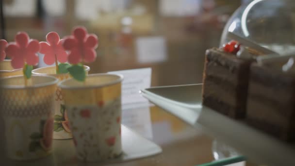 V baru kávu a pečivo. Na pultu brýle s květinami. Zaměstnancem kavárny zveřejňuje připravené dezerty na počítadlo. — Stock video