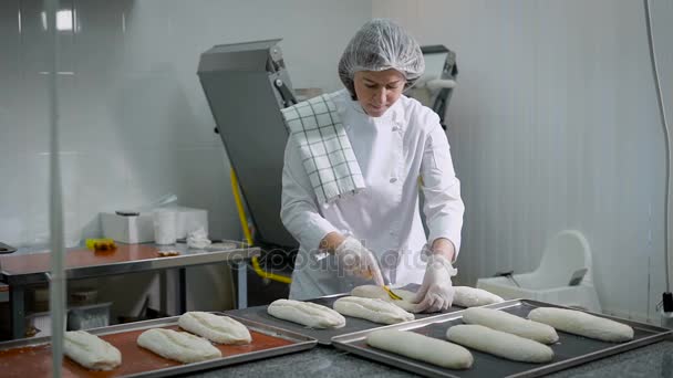 A mulher numa loja de doces. A morena em uma forma branca faz preparações para assar-se do pão. A menina de meia-idade criou uma forma de pão a partir do teste . — Vídeo de Stock