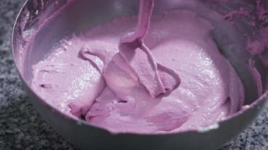 Krem mor renk yavaş yavaş tatlılar yemek pişirmek için pota drenaj. Metal kase'de bir tabloda bir fırın. Kalın tatlı madde.