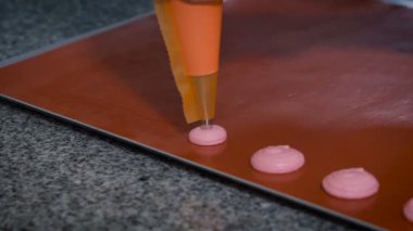 Şef pasta Macaron, daha sonra olabilir fırın pişirme için pembe kağıt krem üzerinde yatıyordu tepsi doldurmaya başlar
