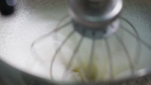 Mixer vänder och vispad grädde med äggvitor i en stekpanna i köket. Vitt skum bildades till följd av utarbetande av sötsaker. — Stockvideo