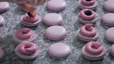 Şekerci dükkânı. Fransızca macaroons dekorasyon. Eldiven bir şekerci dükkanında çalışan için hazır bir tatlı krema ve çilek ekler. Böylece bir tatlı dekorasyon.