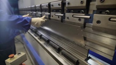 Metal fabrikasında işçi makine koyarak iş parçasına atlayın. Sac ve özel makine bükme aletleri ile çalışan adam. Modern makineleri doğru görevleri gerçekleştirebilirsiniz.