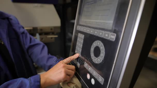 Le travailleur appuie sur les boutons du panneau de la machine-outil avec commande numérique programmée. L'ingénieur configure un programme de fonctionnement de la machine . — Video