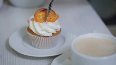 Adam yavaşça adet meyve, beyaz bir daire üzerinde duran ile dekore edilmiş kaşık wch gelen tereyağı krema ile cupcakes bir parça uzakta tatili.