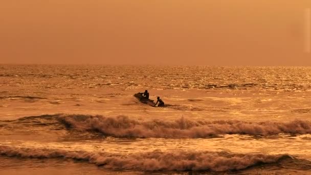 Brillante vista del corredor de olas cortando el océano con dos hombres en él. Imagen de la puesta de sol balinesa con agua marrón y cielo en clima soleado al aire libre con fondo natural . — Vídeos de Stock