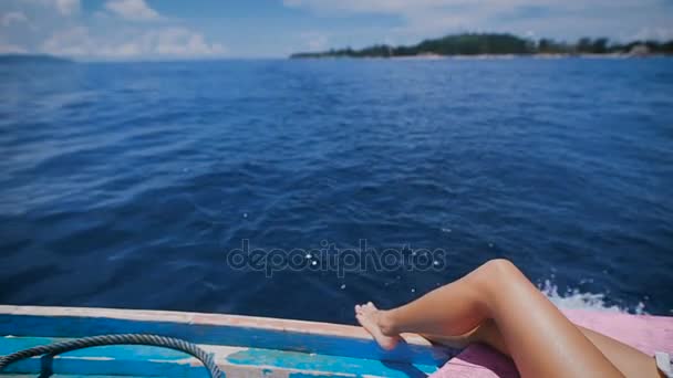 Immagine di gambe sexy di una giovane donna in crociera marina sdraiata sul ponte della barca a vela in mare aperto. Abbronzato piedi nudi di viaggiatore femminile attraversato su uno yacht con oceano e isola sullo sfondo . — Video Stock