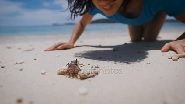 L'isola di Bali. Spiaggia. Artropodi. Bruna sulla spiaggia. Ha visto chlenistonogovo e ha deciso di giocare con lui. La donna ha toccato chlenistonogovo e ha ricevuto molte emozioni positive . — Video Stock