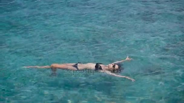 Bali, Indonezja. Ocean. podróży. Brunette ciesząc turkus oceanu. Dziewczyna leży na powierzchni wody i zrelaksować się. Piękna pogoda towarzyszy turysta. — Wideo stockowe