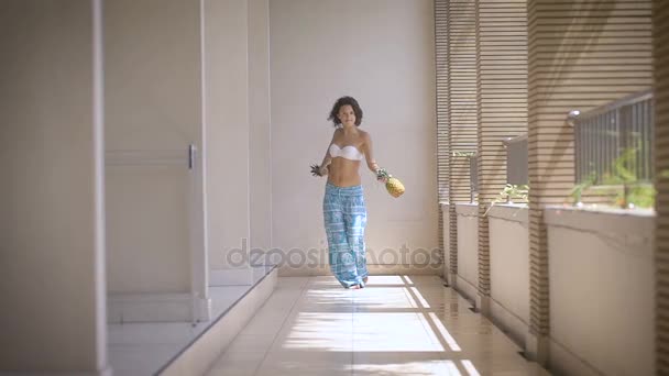 Hotel Corridor. La chica en traje de baño y pantalones azules gratis, en las manos de sus dos piñas. Morena jugó a la piña y muestra un baile español . — Vídeos de Stock