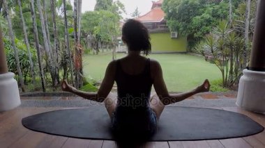 Yağmurlu günde Bali Adası. Kız poz yogi derin derin düşünür. Esmer rahatlatır ve bir dinlenme vardır. Bali ilgilenen kişiler için gerçek Mekke sihirli doğa ile tekrar bir araya için