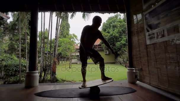 Insel Bali. Der junge Mann trainiert auf einem speziell dafür vorgesehenen Balancierbrett. Der Mann lernt weiter das Gleichgewicht zu halten, es ist richtig, sich auf einem Surfbrett zu halten. Der Typ entwickelt die richtige Ausrüstung. — Stockvideo