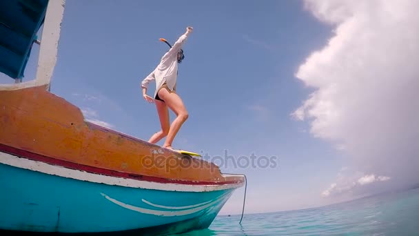 Bella ragazza vestita con una camicia bianca e costume da bagno nero fare una divertente danza a bordo della barca e poi saltare in acqua di mare. Attività ricreative presso il resort . — Video Stock