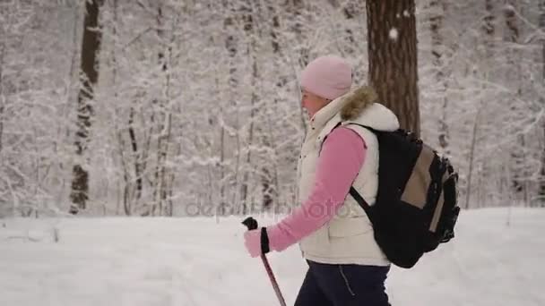 Kobieta szybko przechodzi przez zaśnieżony Las. Ona spada nieco pod śniegiem, bo to nowa ścieżka. Za jej wisi duży plecak czarny są rzeczy osobiste. — Wideo stockowe