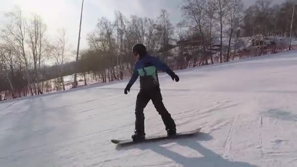 Mann steigt schnell mit Snowboard vom Berg Sein Körper wird durch spezielle Ausrüstung geschützt - schwarze Mütze, Sonnenbrille für die Augen, Handschuhe, Jacke, Hose, die nicht nass wird. — Stockvideo