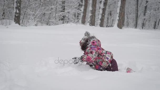 Nahaufnahme einer wunderbaren Familie, die zusammen im Winterwald spielt. Eine junge Frau sitzt im Schnee und wartet auf ihre kleine Tochter. Kleines Mädchen drängelt sich durch die Schneewehen zu seiner Mutter. — Stockvideo