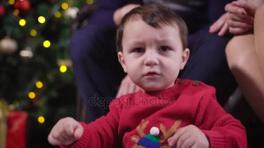 Bebek portre. Bir çocuk bir geyik yavrusu ile kırmızı kazaklı kameraya bakıyor. Çocuk çok ciddidir. Veliler ve güzel arka plan karşı Oda dekore edilmiştir..