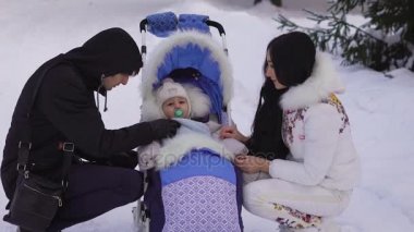 Mutlu evli çift battaniye sadece tekerlekli sandalyede oturan ve bir emzik ağzında tutarak onun küçük çocuk düzeltiyor. Bir kadın bir bebek her şeyi iyi olup olmadığını kontrol etmek için bir emzik alır..