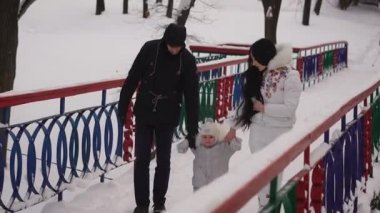 Kış. Genç aile demir köprünün üzerinde yürüme. Bir adam ve bir bebek elinde tutan bir kadın. Bebek büyük dünya onun ilk adımlarını atıyor. Kış yürüyüşleri vücut sertleşmesine.
