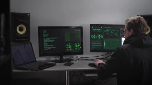 Close up van een spion met smartwatch en mobiele telefoon zitten aan de tafel met computer-monitoren. Hacker proberen ongeoorloofde toegang te verkrijgen tot belangrijke informatie door hacking database. — Stockvideo