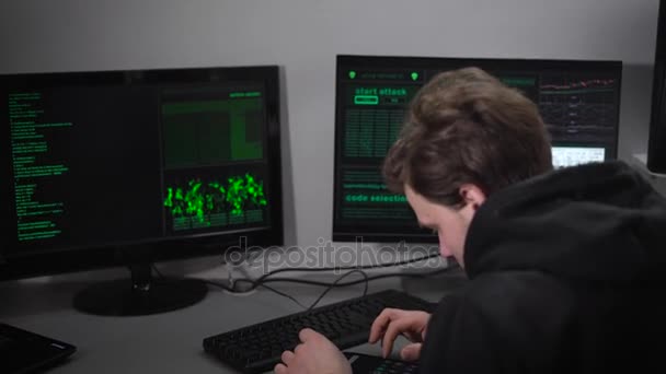 Sala computer nel seminterrato. Un uomo controlla le informazioni sul tuo smartphone. Le informazioni sul computer vengono visualizzate in questo momento. L'hacker cerca di entrare in informazioni importanti . — Video Stock