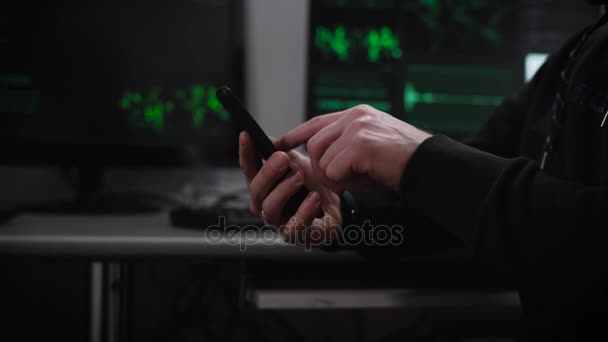 Hacker introduce rápidamente códigos desde las pantallas de la computadora en el teléfono inteligente. En el fondo de los monitores analizan grandes cantidades de información para una variedad de sistemas de E-hacking . — Vídeo de stock