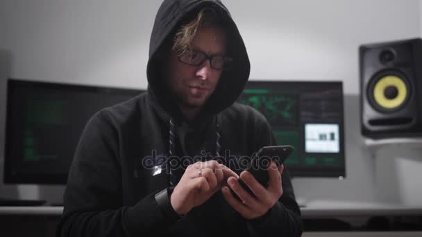 Hombre tenso con chaquetas con capucha por color, con gafas de borde negro en los ojos, pelo castaño y barba de barba sentado en la silla y el estrés está escribiendo un mensaje en la pantalla táctil — Vídeos de Stock