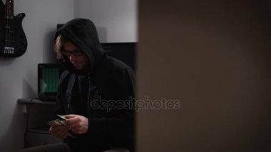 Bir hacker bilgisayar odasında. Bir ceket kukuleta, gözlük ve para elinde bir sandalyede oturan bir adam. Para saymak için bir adamla mutlu bir ruh hali. Sarışın adam leer kameraya bakıyor.