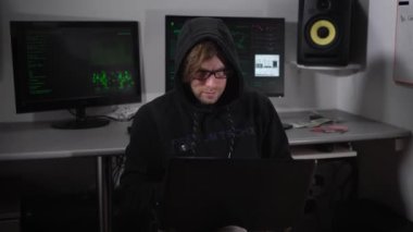 Rahat oturma odasında onun arkasında bilgisayar monitörleri ile dizüstü bilgisayar üzerinde çalışan siyah genç hacker. Konsantre erkek casus yazarak hızlı çalmak veri ve bilgisayar ağı üzerinden önemli bilgiler.