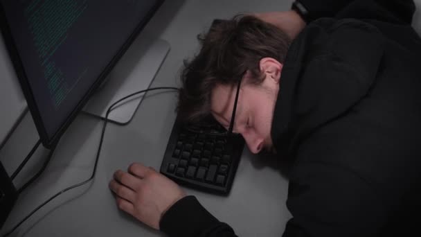 Joven estudiante de la Facultad de Tecnología de la Información está durmiendo en el teclado en la parte inferior del monitor de la computadora después de estudiar duro. El hombre está cansado y descansando antes de las clases después de aprender toda la noche . — Vídeos de Stock