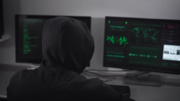 Задний вид на хакера, который занимается тайными кибератаками на сервер с помощью банка данных. Culprit в сфере ИТ получает незаконный доступ к средствам в Интернете . — стоковое видео