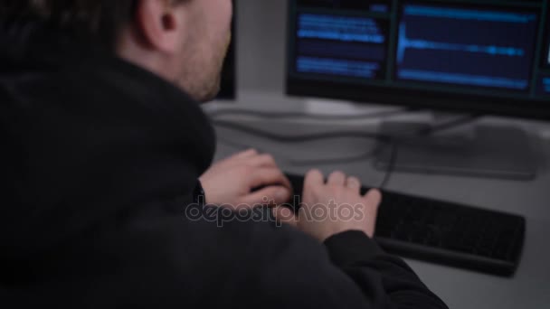 Vista posterior de un hacker sentado y haciendo ciberataque en la red. Hombre con ropa negra está escribiendo rápido en el teclado tratando de entrar en el sistema, pero el mensaje sobre el acceso denegado apareció en la pantalla . — Vídeo de stock