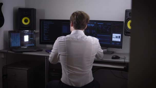 Unga systemutvecklare analyserar och presenterar en stor mängd elektroniska data medan du arbetar på ett nytt projekt. Ett par monitorer och en laptop som används vid arbete på komplexa program. — Stockvideo