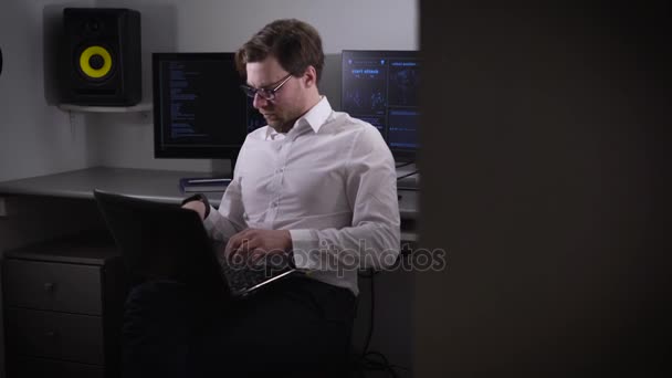 Програміст готується до налаштування обладнання в комп'ютерній кімнаті. Людина з початковою швидкістю вводить інформацію в ноутбук. Комп'ютерна кімната оснащена найкращими технологіями . — стокове відео