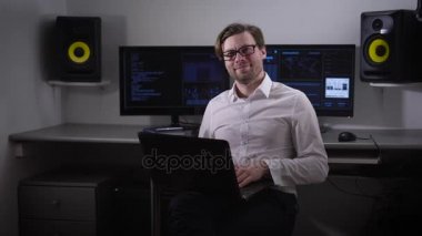 Görünümü bir mutlu ve düşünceli programlama, ofis çalışanı, dondu. Onun elinde bir dizüstü bilgisayar ve bir gülümseme oturmuş, koordinat yüzünde dondu.