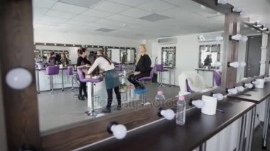 Lüks güzellik salonu modern tarzda tasarlanmış iç alışılmadık açıdan gösterdi. Masters ve istemciler Studio bir aynada kendi birlikte çalışma sırasında lambalar ile yansıtılır.